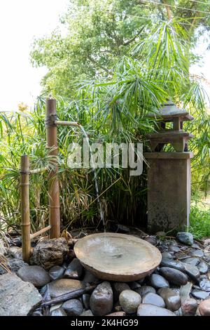 Kleiner asiatischer Brunnen mit Bambus, Flusssteinen und fallendem Wasser in mexiko Stockfoto