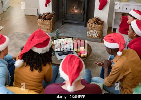 Biracial Freunde in santa Hüte auf Laptop weihnachten Videoanruf mit der Familie. . weihnachten, Fest und Kommunikationstechnik. Stockfoto