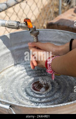 Awoman wusch sich draußen die Hände, in einem provisorischen Waschbecken aus Metall und Pfeifen. mexiko Stockfoto