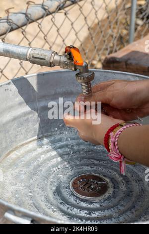 Awoman wusch sich draußen die Hände, in einem provisorischen Waschbecken aus Metall und Pfeifen. mexiko Stockfoto