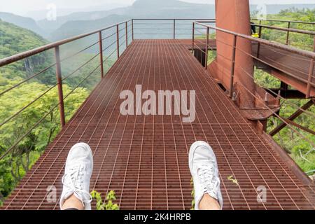 Verrostete alte Seilbahn, Seilbahnfahrt im Regen, Blick auf den Canyon, die Vegetation und die Menschen. Mexiko Stockfoto