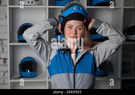 Kaukasische Frau setzt sich einen Helm an, bevor sie in einem Windkanal fliegt. Free Fall Simulator. Stockfoto