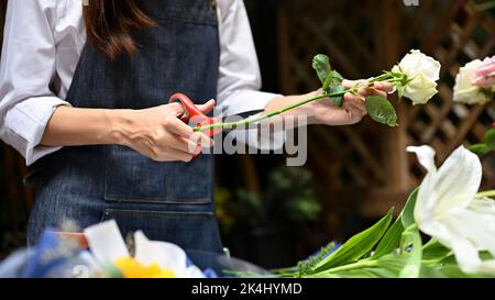 Eine Floristin oder ein Blumenhändler, die einen schönen Strauß macht, indem sie mit einer Schere einen Blütenstiel schneidet Stockfoto