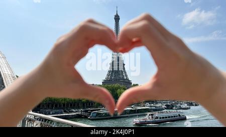 Ein wunderschönes Mädchen im Teenageralter blickt in den Rahmen und lehnt sich vor der Kulisse des Eiffelturms, lächelt sie und scheint Come Here großartige Werbung für eine Reise nach Paris zu zeigen. Hochwertige Fotos Stockfoto