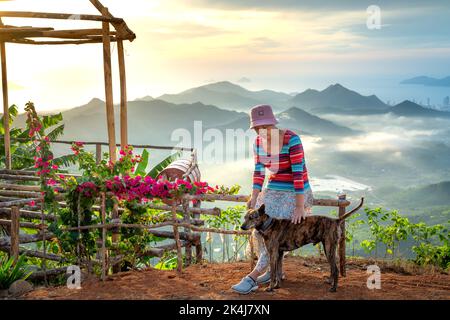 Nha Trang, Khanh Hoa, Vietnam - 23. August 2022: Eine weibliche Touristin spielt mit ihren beiden Haustierhunden auf einem hohen Berg in Nha Trang, Khanh Hoa, Vietnam Stockfoto