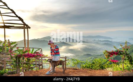 Nha Trang, Khanh Hoa, Vietnam - 23. August 2022: Eine weibliche Touristin spielt mit ihren beiden Haustierhunden auf einem hohen Berg in Nha Trang, Khanh Hoa, Vietnam Stockfoto