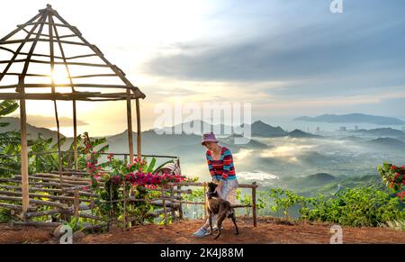 Nha Trang, Khanh Hoa, Vietnam - 23. August 2022: Eine weibliche Touristin spielt mit ihren beiden Haustierhunden auf einem hohen Berg in Nha Trang, Khanh Hoa, Vietnam Stockfoto