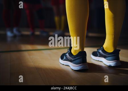 Nahaufnahme von Frauenbeinen in Kniesocken und Sportschuhen vor dem Unihockey mach im Fitnessstudio. Stockfoto