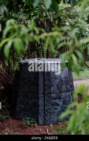 Plastikkompostkasten im Garten. Konzept der Abfalltrennung, Wiederverwendung von Abfällen, Dünger. Stockfoto