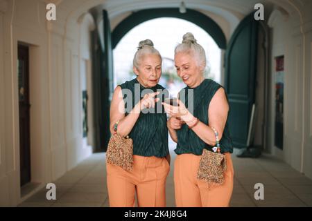 Ältere Frauen Zwillinge im Freien in der Stadt überprüfen Smartphone. Stockfoto