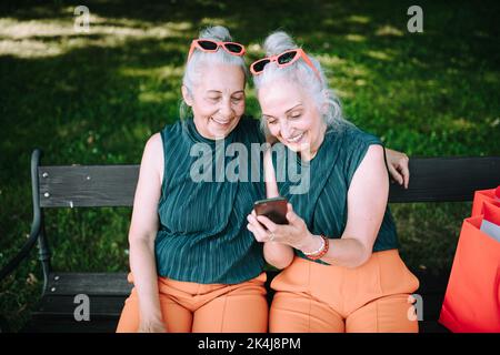 Ältere Frauen Zwillinge im Freien in der Stadt überprüfen Smartphone. Stockfoto