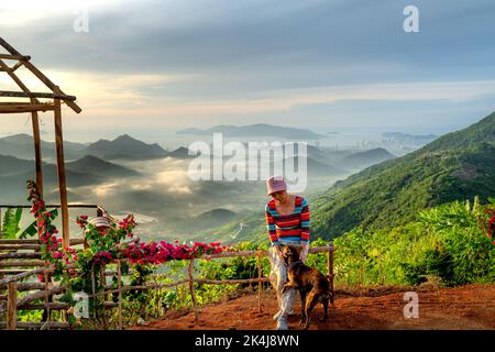 Nha Trang, Khanh Hoa, Vietnam - 23. August 2022: Eine weibliche Touristin spielt mit ihren beiden Haustierhunden auf einem hohen Berg in Nha Trang, Khanh Hoa, Vietnam Stockfoto