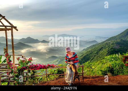 Nha Trang, Khanh Hoa, Vietnam - 23. August 2022: Eine weibliche Touristin spielt mit ihren beiden Haustierhunden auf einem hohen Berg in Nha Trang, Khanh Hoa, Vietnam Stockfoto