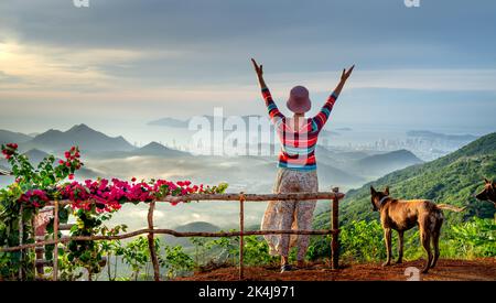 Nha Trang, Khanh Hoa, Vietnam - 23. August 2022: Eine weibliche Touristin spielt mit ihren beiden Haustierhunden auf einem hohen Berg in Nha Trang, Khanh Hoa, Vietnam Stockfoto