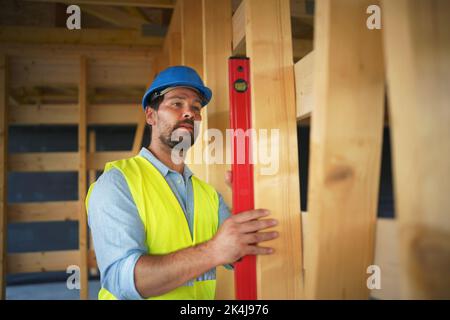 Zimmermann überprüft Holzbretter mit Wasserwaage, diy umweltfreundliche Häuser Konzept. Stockfoto