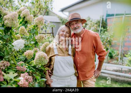 Verliebte ältere Paare posieren gemeinsam in ihrem Garten. Stockfoto