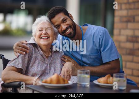 Pfleger beim Frühstück mit seinem Kunden im Café. Stockfoto