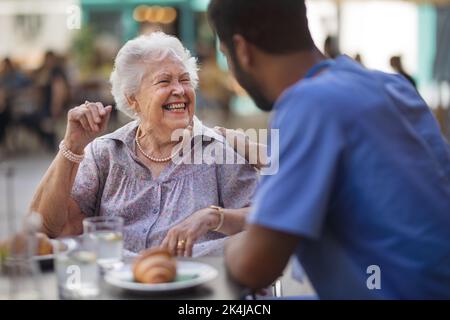 Pfleger beim Frühstück mit seinem Kunden im Café. Stockfoto