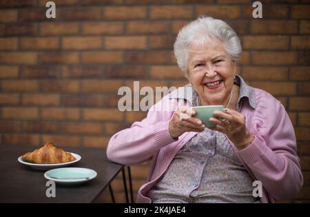 Eine glückliche ältere Frau, die im Café in der Stadt frühstücken kann. Stockfoto