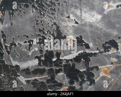 Brauner Rostfleck auf der schwarzen mit blau mit grün mit grau und silberfarben Oberfläche des Blechs, rissige und abblätternde Oberflächen Stockfoto