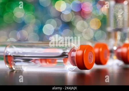 Nahaufnahme der Medizin zur Injektion in Glasfläschchen auf einem farbenfrohen Hintergrund Stockfoto