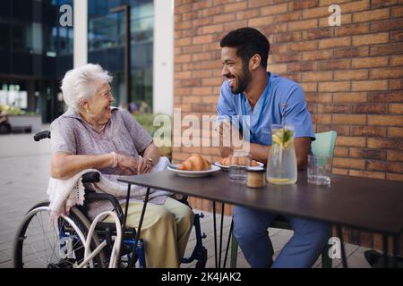 Pfleger beim Frühstück mit seinem Kunden im Café. Stockfoto