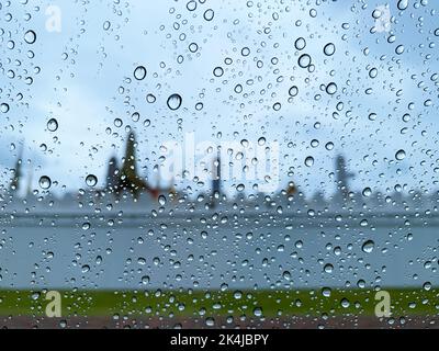 Selektiver Fokus auf Wassertropfen auf dem Autoglas bei Regen in der Monsunsaison mit verschwommenem Hintergrund. Stockfoto