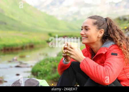 Wanderer lächelnd trinkender Kaffee, sitzend und ruhend im Berg Stockfoto