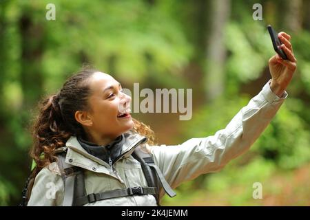 Glücklicher Wanderer, der in einem Wald steht und Selfie mit dem Telefon macht Stockfoto