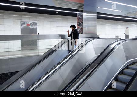 Moskau. Russland. 2. Oktober 2022. Ein junger schwarzer Mann steigt an einer U-Bahnstation auf eine Rolltreppe herab. Stockfoto