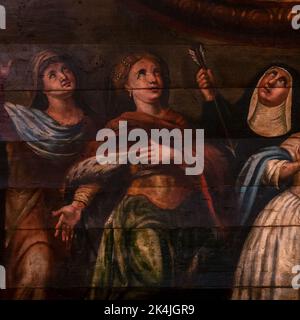 Eine Nonne greift einen Pfeil, während sie steht, mit Blick nach oben in den Himmel, mit anderen weiblichen Heiligen und Märtyrern in diesem quadratischen Detail eines Frieses, der Anfang der 1700er Jahre im rustikalen Barockstil gemalt wurde, unter dem Deckengewölbe der Eglise Saint-Martin (Kirche St. Martin) in Lévignacq in den Landes, Nouvelle-Aquitaine, Frankreich. Stockfoto