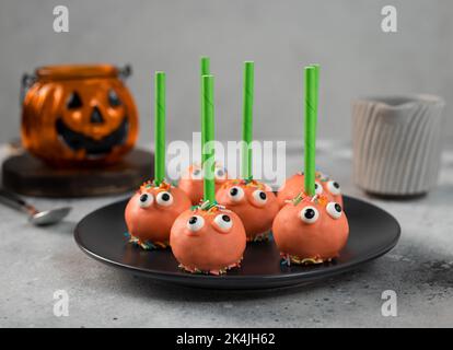 Halloween Kuchen knallt mit lustigen Gesichtern auf dunklem Teller Stockfoto