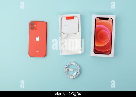 Tjumen, Russland-18. Juli 2022: IPhone 12 mini Produkt rot mit Einzelhandelsverpackung. Draufsicht, blauer Hintergrund Stockfoto