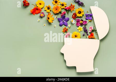 Welttag der psychischen Gesundheit Konzept. Papier menschlichen Kopf Symbol und Blumen auf blauem Hintergrund Stockfoto