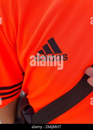 Tjumen, Russland-30. August 2022: Adidas Logo auf orangefarbenem T-Shirt. Adidas ist ein deutscher multinationaler Konzern für die Herstellung von Bekleidung und Fußbekleidung Stockfoto