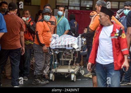 Malang, Indonesien. 2. Oktober 2022. Die Menschen übertragen die Leiche eines Opfers in ein Krankenhaus in Malang, Ost-Java, Indonesien, 2. Oktober 2022. SO GEHT ES WEITER mit „FIFA sagt „das ist ein dunkler Tag“ für den Fußball nach der Tragödie im indonesischen Stadion“ Credit: Bisinglasi/Xinhua/Alamy Live News Stockfoto