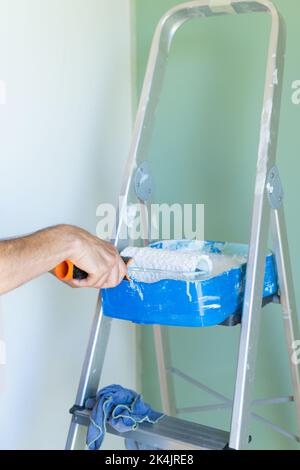 Leiter des Malers und handwringende Farbrolle. Der Innenraum des Hauses. Mann malt das Haus, Nahaufnahme. Stockfoto