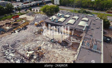 06.08.2022 - Warschau, Polen - die Abrissstelle. Schwere Maschinen, Bagger zerstören ein riesiges altes Gebäude. Freiraum für den Bau eines neuen. Drone-Ansicht von oben. Hochwertige Fotos Stockfoto
