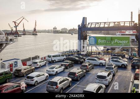 Autos, die auf dem Autodeck der Stena Jutlandica Fähre am Fährhafen von Göteborg, Schweden, geparkt sind. Ein großes Schild, das anzeigt, dass die Fähre teilweise batteriebetrieben ist, ist am Heck des Schiffes zu sehen. Stockfoto