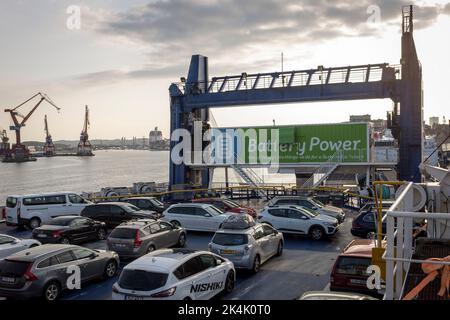 Autos, die auf dem Autodeck der Stena Jutlandica Fähre am Fährhafen von Göteborg, Schweden, geparkt sind. Ein großes Schild, das anzeigt, dass die Fähre teilweise batteriebetrieben ist, ist am Heck des Schiffes zu sehen. Stockfoto
