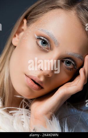 Porträt der blonden jungen Frau mit Winter Make-up Blick auf Kamera isoliert auf blau, Stock Bild Stockfoto