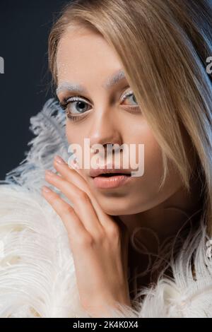 Porträt einer jungen Frau mit weißen Federn Blick auf Kamera isoliert auf dunkelblau, Stock Bild Stockfoto