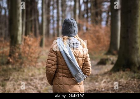 Frau in warmer Kleidung bei kaltem Herbstwetter. Spaziergang im Wald im Herbst Stockfoto