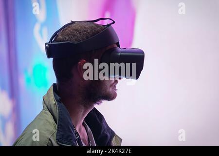 Virtual-Reality-Ausstellung. Der junge Mann trägt eine Virtual-Reality-Brille und erlebt eine metaverse Begegnung. Turin, Italien - September 2022 Stockfoto