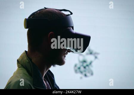 Virtual-Reality-Ausstellung. Der junge Mann trägt eine Virtual-Reality-Brille und erlebt eine metaverse Begegnung. Turin, Italien - September 2022 Stockfoto