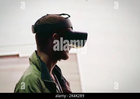 Virtual-Reality-Ausstellung. Der junge Mann trägt eine Virtual-Reality-Brille und erlebt eine metaverse Begegnung. Turin, Italien - September 2022 Stockfoto