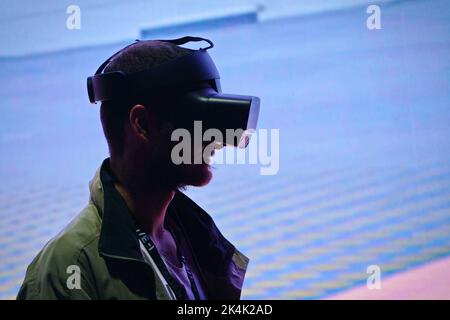 Virtual-Reality-Ausstellung. Der junge Mann trägt eine Virtual-Reality-Brille und erlebt eine metaverse Begegnung. Turin, Italien - September 2022 Stockfoto