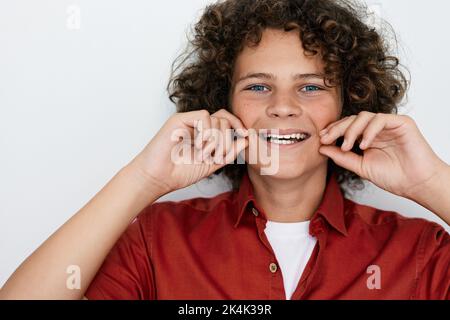 Porträt eines lockigen Jungen mit weißem, gesundem Lächeln. Kinderzähne Gesundheitskonzept Stockfoto