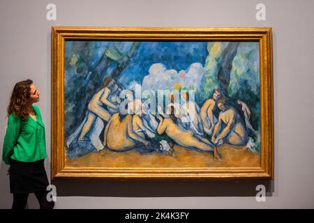 London, Großbritannien. 3. Oktober 2022. Ein Mitarbeiter blickt auf „Baders (Les Grandes Baigneuses)“, c. 1894-1905, beide von Paul Cezanne bei der Vorschau der EY-Ausstellung: Cezanne in der Tate Modern. Vom 5. Oktober bis 12. März 2023 werden 80 Gemälde, Aquarelle und Zeichnungen von Paul Cezanne mit Schlüsselbeispielen seiner ikonischen Stillleben-Gemälde, Provençale-Landschaften, Porträts und Baderszenen, darunter über 20 Werke, die in Großbritannien noch nie zu sehen waren, gezeigt. Kredit: Stephen Chung / Alamy Live Nachrichten Stockfoto