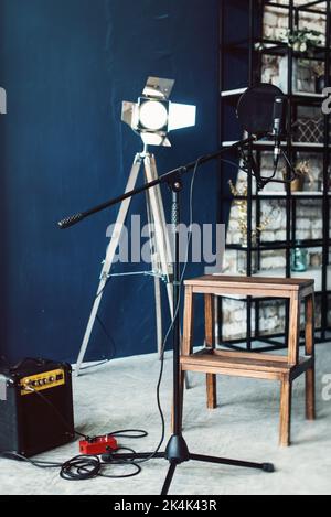 studio-Kondensatormikrofon mit POP-Filter und vibrationsgedämpfter Live-Aufnahme. Blaue Wand, Lautsprecher und dekorative Beleuchtung auf einem Hintergrund Stockfoto